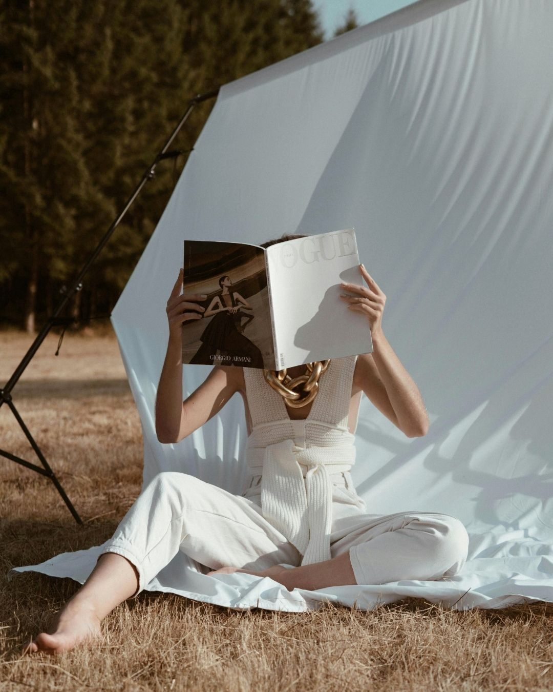 Coaching pour femmes bordeaux Femme assise sur l'herbe, tenant un livre devant son visage, vêtue de blanc.